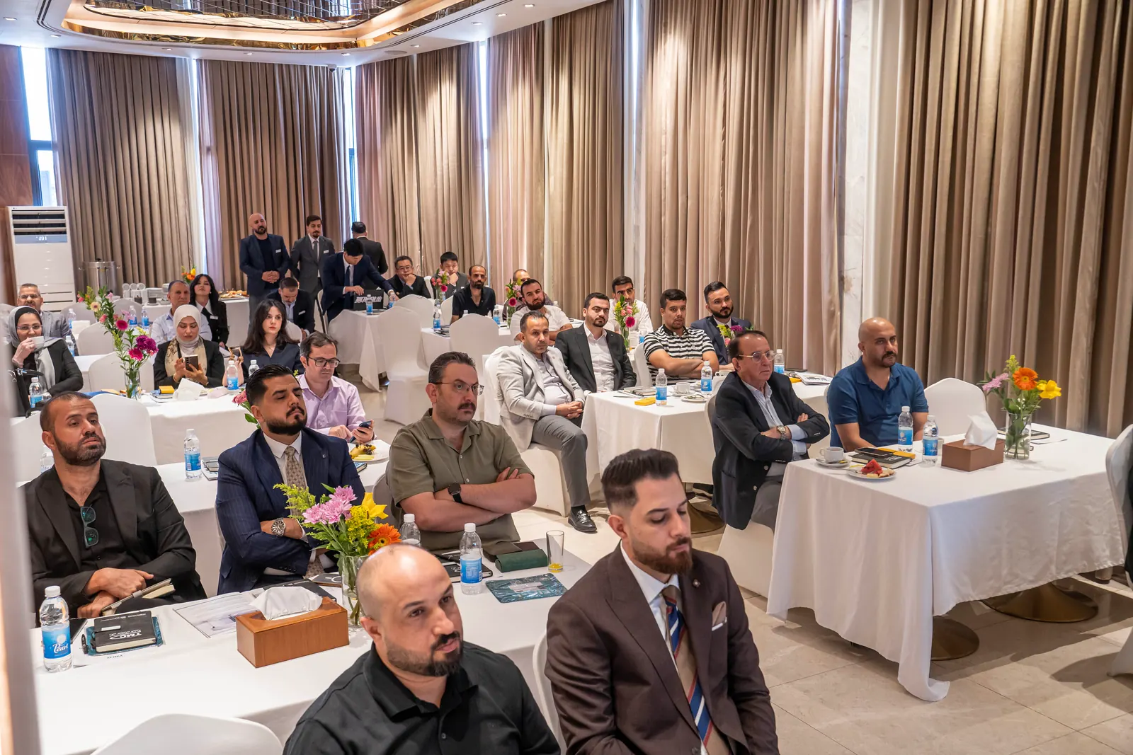 Rows of attendees seated at round tables in a hotel conference hall during the scientific day